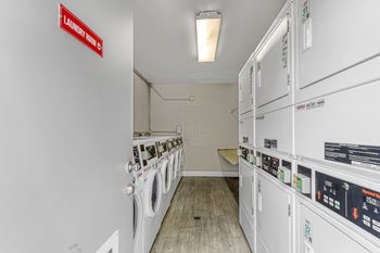 A laundry room with washing machines and a red sign on the wall.